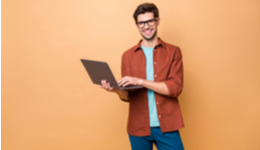 Man smiling using laptop on bright background